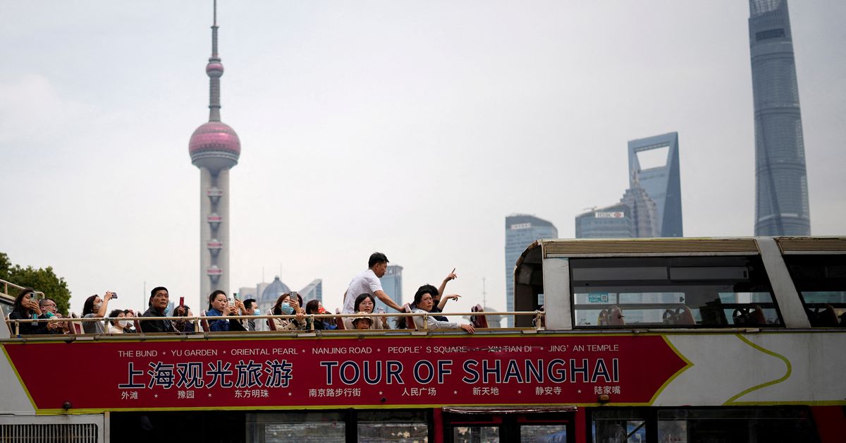 Tourists ride on a tourist double-decker bus in the Bund in Shanghai
