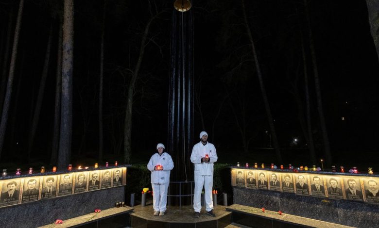 Staff of the Chornobyl nuclear plant hold candles at a memorial dedicated to firefighters and workers who died after the Chornobyl nuclear disaster, during a night commemorative service in Slavutych