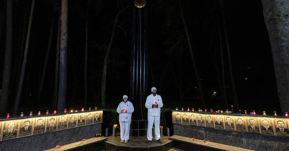 Staff of the Chornobyl nuclear plant hold candles at a memorial dedicated to firefighters and workers who died after the Chornobyl nuclear disaster, during a night commemorative service in Slavutych