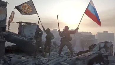 Wagner mercenary group fighters wave flags on top of a building in an unidentified location
