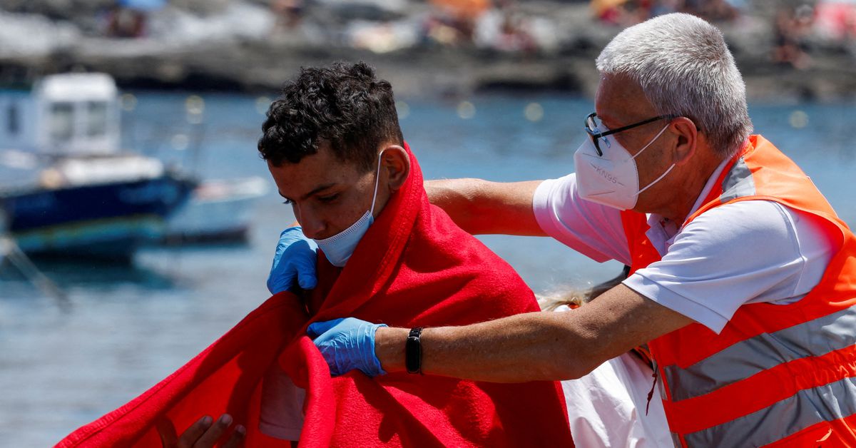 A member of the Red Cross assists a migrant after disembarking from a Spanish coast guard vessel, at the port of Arguineguin